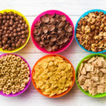 top view of various kids cereals in colorful bowls on wooden tab